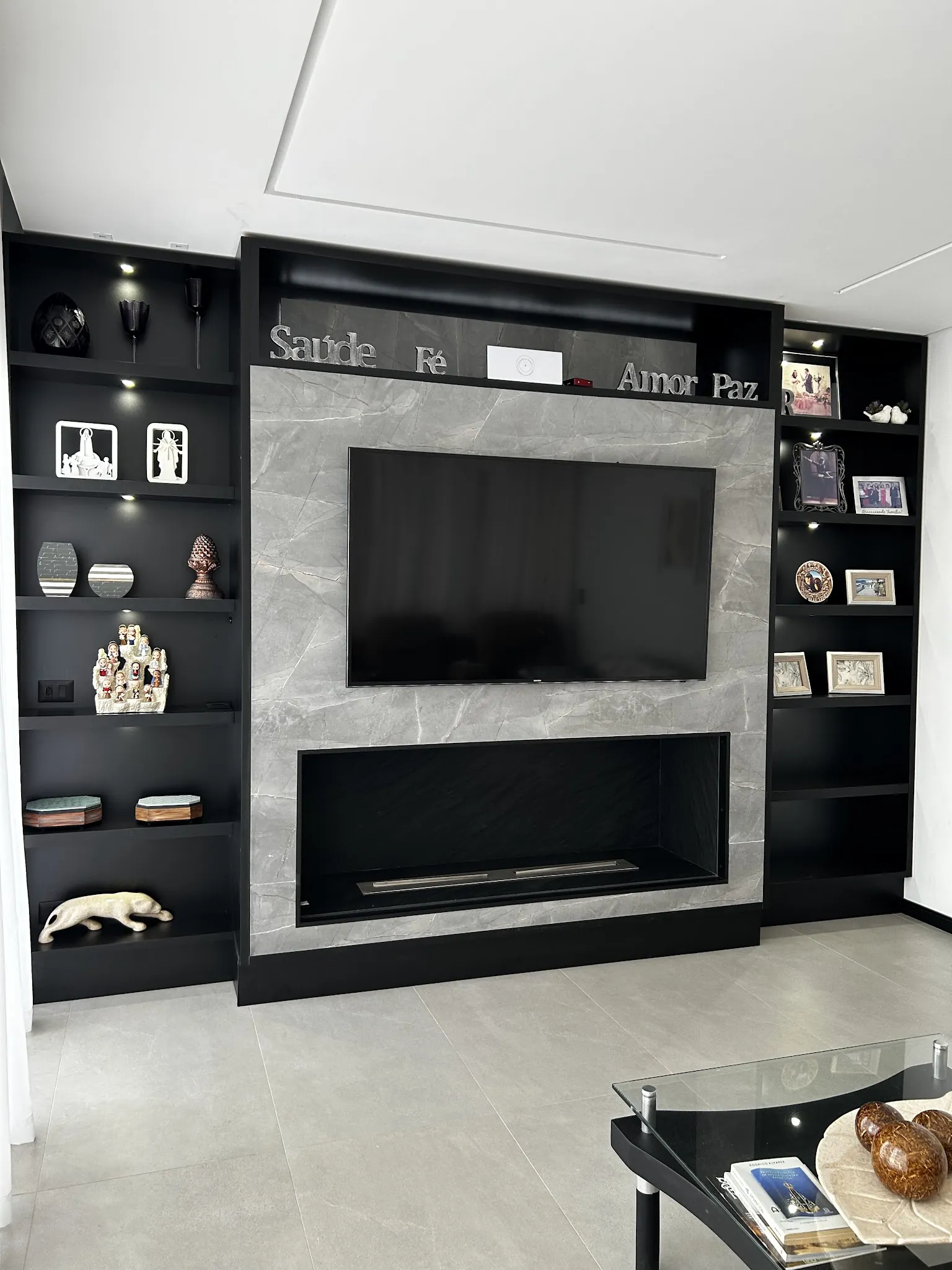 Sala com painel escuro, lareira embutida e nichos com objetos